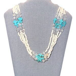 Multi-strand statement necklace features turquoise-colored cross beads